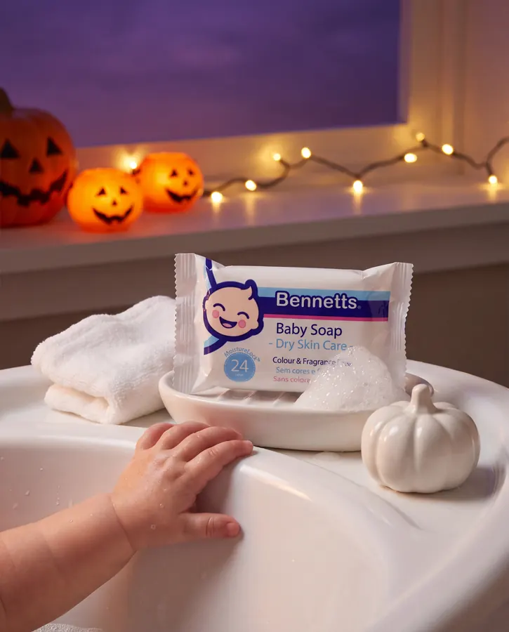 Bennetts Baby Soap on a soap dish at the edge of the bath, with jack-o’-lanterns and a baby’s hand on the rim