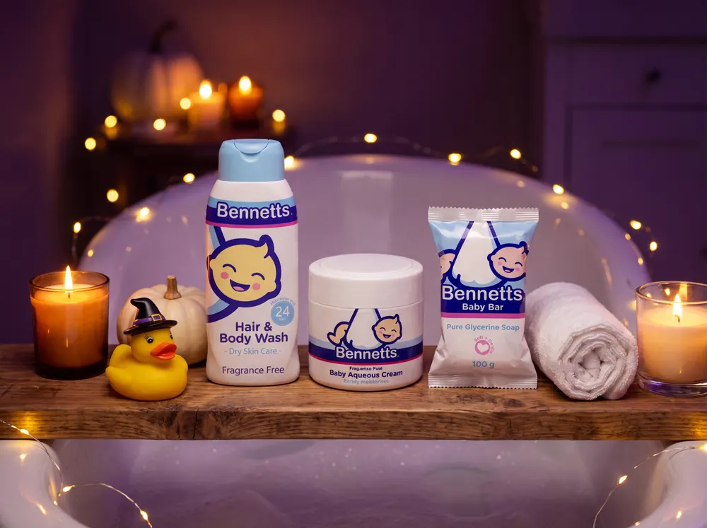 Bennetts Hair & Body Wash, Aqueous Cream and a Baby Bar on a bath board with candles and a rubber duck