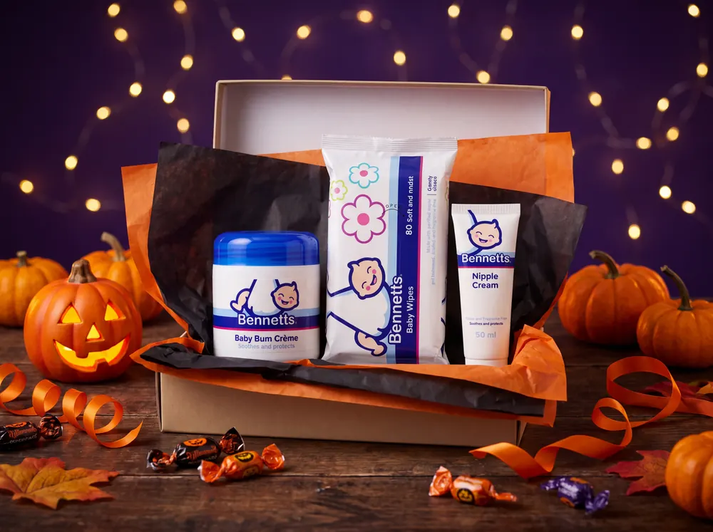 A gift box with orange and black tissue holding Bennetts Baby Bum Crème, Baby Wipes and Nipple Cream